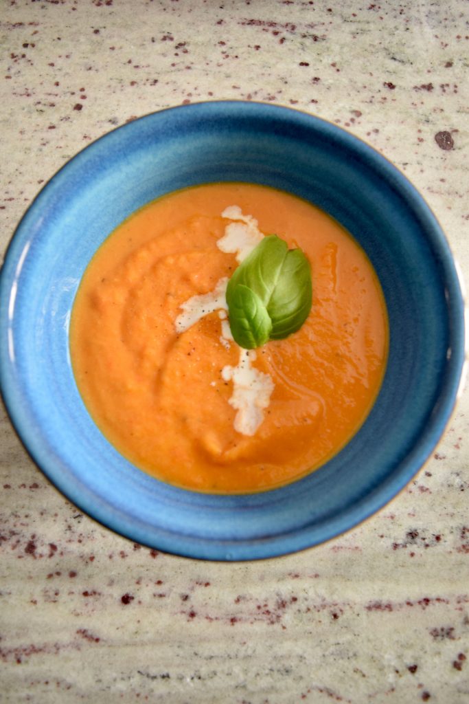 one bowl of squash soup topped with cream and basil