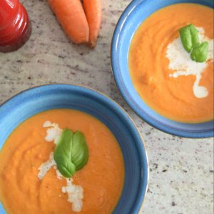 two bowls of squash soup, topped with cream and a basil leaf