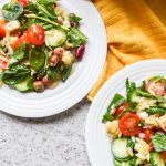 close up shot of 2 white plates filled with fresh orzo salad and vegetables