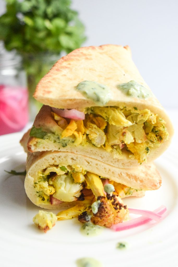2 wraps stacked on top of each other filled with chicken, cilantro yogurt, roasted cauliflower and pickled red onion.