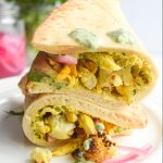 2 wraps stacked on top of each other filled with chicken, cilantro yogurt, roasted cauliflower and pickled red onion.