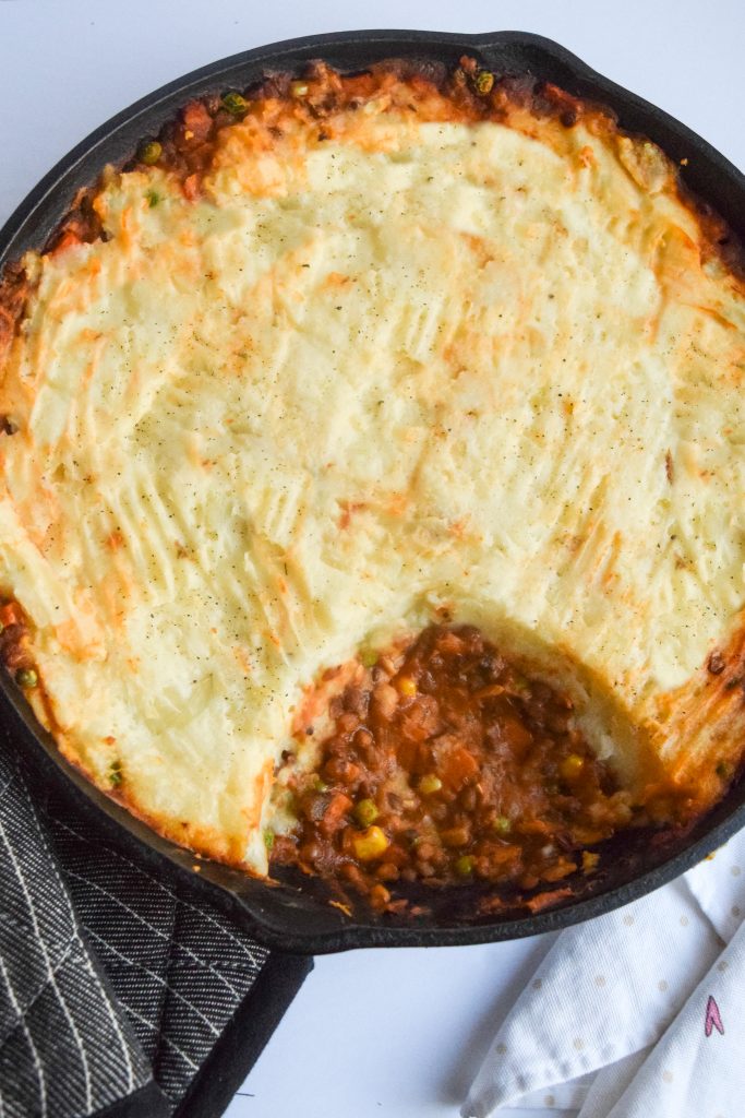 vegetarian shepherd's pie on a white backdrop, white tea towel on right side