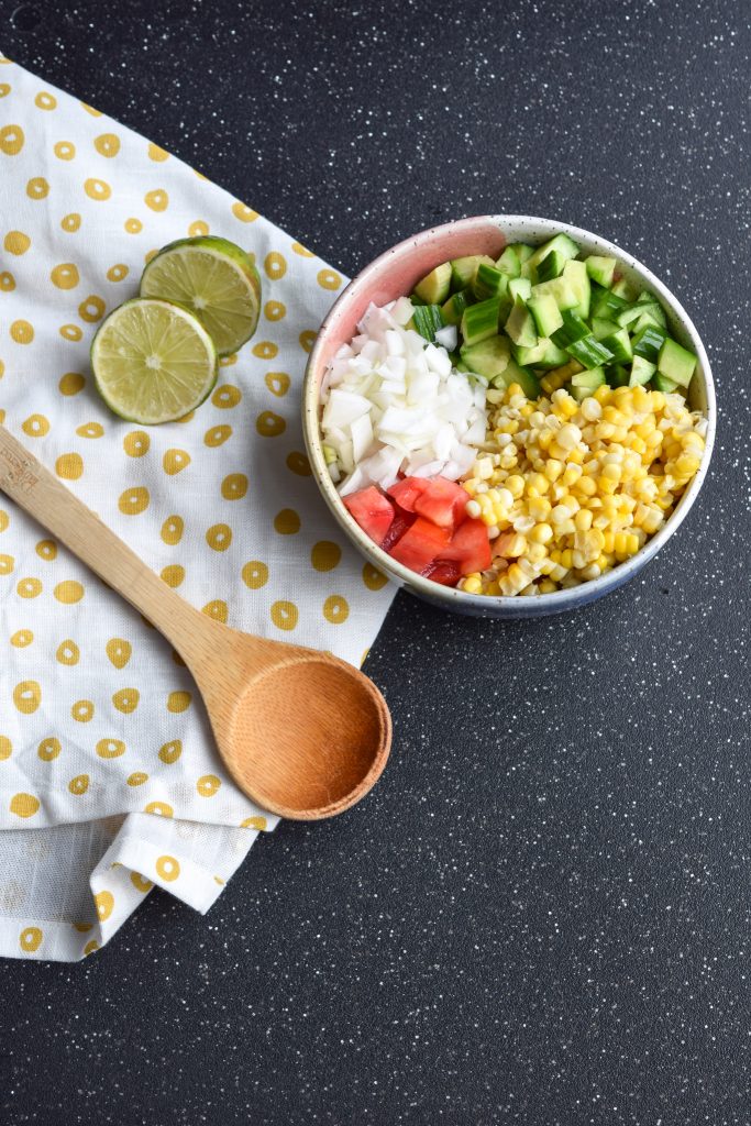 Bowl of chopped tomatoes, corn, cucumbers and onions.