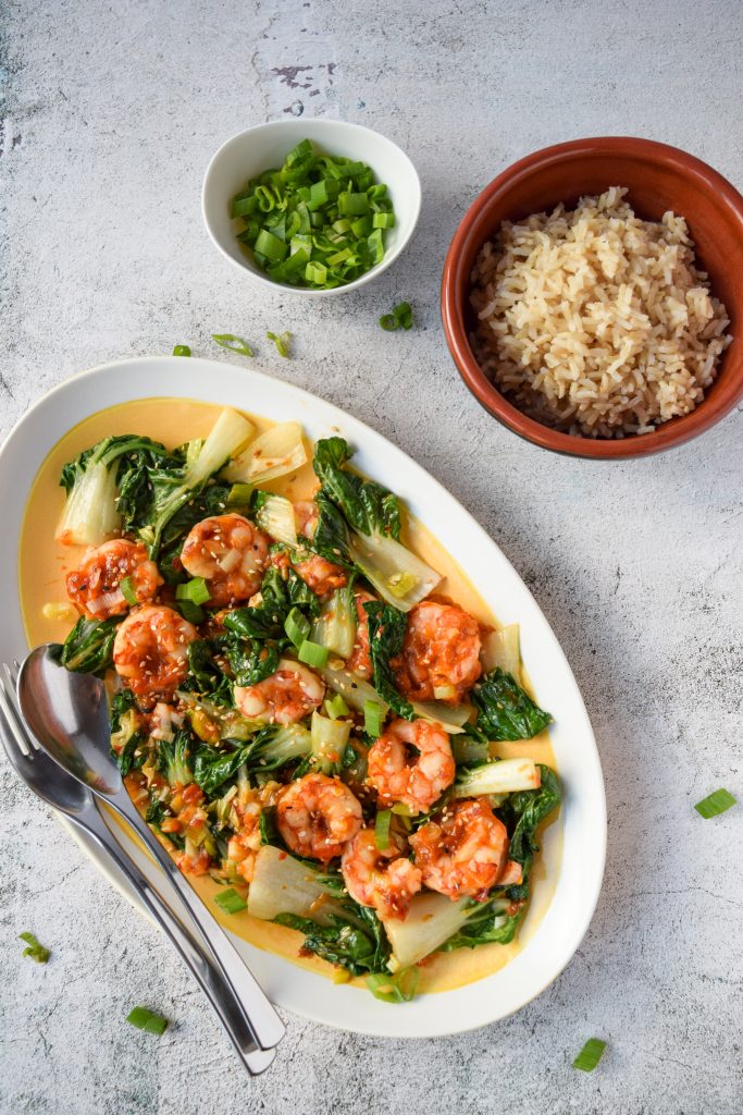 Overhead shot of an oblong white and yellow dish of shrimp and bokchoy.