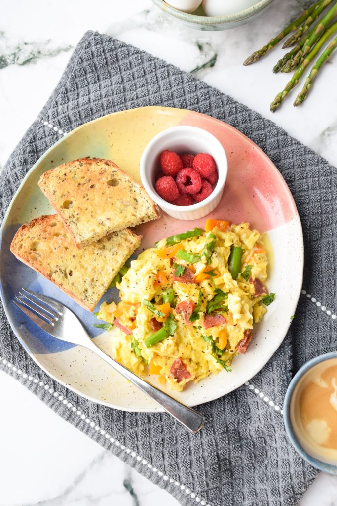 Colourful plate with an egg scramble, toast and raspberries