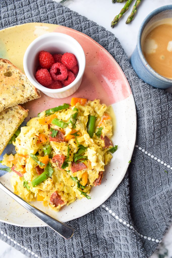 Colourful plate with an egg scramble, toast and raspberries