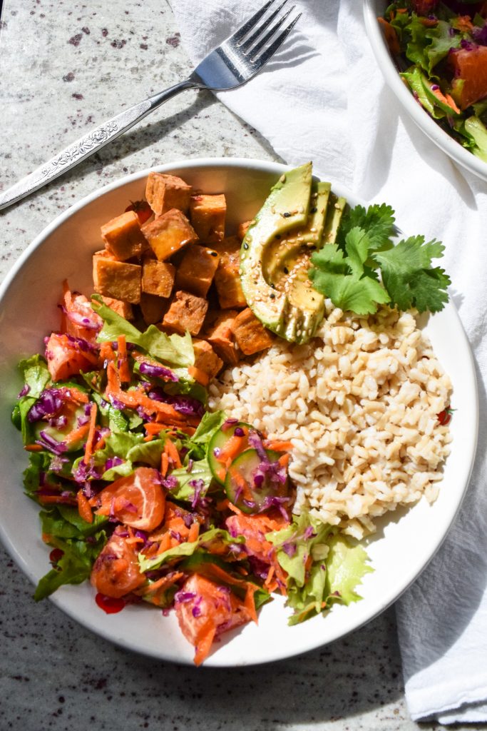 close up shot on a tofu bowl with citrus salad, avocado and brown rice