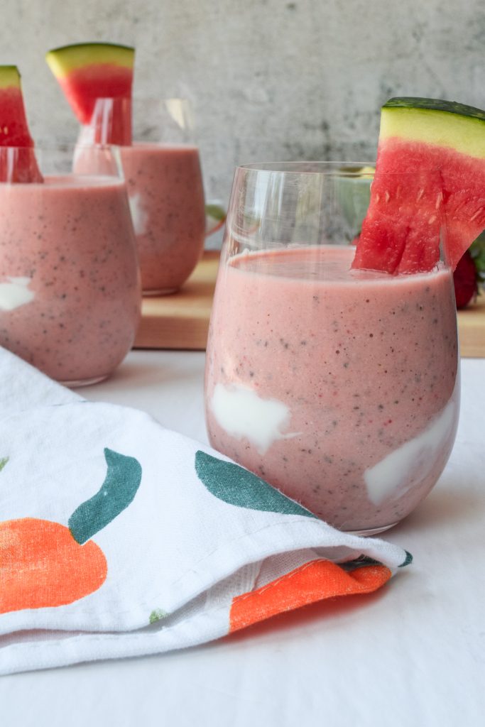 close up shot of 3 watermelon and fruit smoothies topped with a slice of watermelon