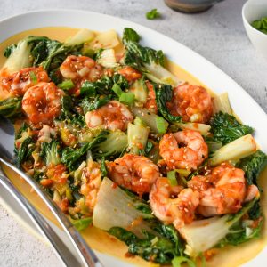Close up shot of an oblong yellow and white dish filled with garlic shrimp and bokchoy.